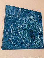 Front view of square 12x12 inch canvas showing blue and white marbled patterns with fluid shapes.