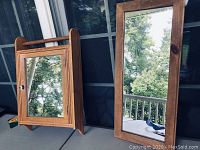 Medicine cabinet and wall mirror on a table with outdoor background showing wooden frame and reflective glass surfaces