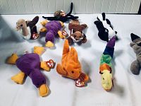 Full lot of 10 TY Beanie Babies plush toys including a variety of duck, fox, skunk, and other animals laid out on white surface with visible TY tags.