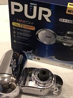 Photo showing the PUR Maxion faucet water filter device with chrome finish and box packaging.