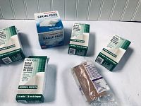 Photo showing multiple boxes of Assured rolled gauze and CVS pharmacy sterile gauze pads on a white surface
