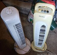 Photo showing two of the heater fans, one beige Pelonis standing fan model FS10-S1, and one white tower fan heater.