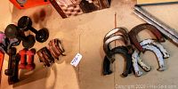 Overview of dumbbells, leather wrist weights, and horseshoes with spikes on the floor.