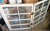 Photo of hinged double window unit showing wooden/light-colored frames, two panels connected by hinges, and glass panes marked with writings