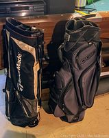 Two golf bags standing upright against a wooden surface, TaylorMade stand bag on the left, Ogio cart bag on the right.