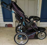 Side view of Baby-Trend jogging stroller in black with blue accents and three large wheels.