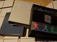 Three binders (white, blue, black album) on tabletop