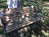 Full view of the cast iron and wooden bench outdoors against tree