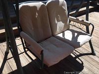 Front view of the two-person patio swing with beige cushions