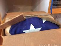 Flag partially visible inside a cardboard box showing a white star on blue field.