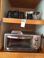 View of the lot inside a cupboard shelf showing Oster toaster oven below and Century toaster, Toastmaster chopper, and Black & Decker coffee maker grouped on top shelf.