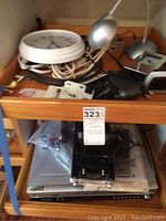 Photo showing the lot items on wooden shelves, including the white wall clock, two silver gooseneck lamps, Chevy car cassette rewinder, small alarm clock, and other accessories.