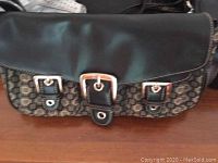 Black and patterned handbag with belt buckle details on front flap