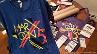 Blue Maroon 5 T-shirt front with large colorful logo, VIP tags, ticket stubs, and a purple T-shirt.