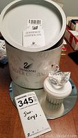 Full lot including original Swarovski cylindrical packaging, certificate, swan crystal figurine on white display pedestal, and display mirror underneath.