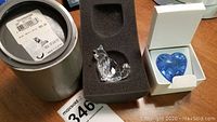 Clear Swarovski crystal cat figurine seated in black foam inside cylindrical box with label.