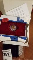 Swarovski crystal flower figurine displayed on red velvet inside blue box with certificate and a separate bag of clear heart crystal pieces below.