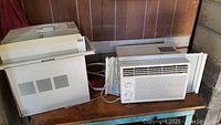 Two window air conditioners: Quasar and Frigidaire, side by side showing front and side views in used condition