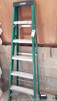 Front and side views of 6-foot Husky aluminum step ladder with green frame and black top cap