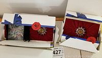 Two Swarovski crystal flowers in original boxes with blue ribbon and red velvet lining, plus bag of small crystal hearts.