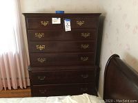 Front view showing 7 drawer dresser with brass handles and dark finish