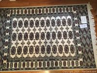 Full view of the modern Oriental rug showing the beige background with red and black medallions and border designs.