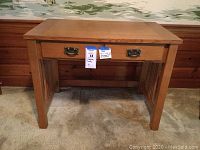 Front view of the oak computer desk showing the drop-down keyboard front panel with metal handles and a solid top surface.