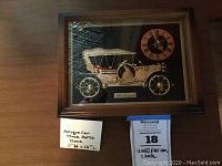 Framed art piece showing a 1910 Touring Car composed of clock parts and a quartz clock with Roman numerals inside a wooden frame.