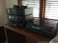Four stacked Onkyo audio components with cables on top, including a turntable with dust cover on the right side.