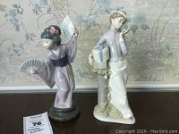 Front view of both women figurines, Lladro Asian woman in kimono with fans, Nadal woman with hat boxes.
