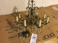 Overall chandelier on cardboard with visible metal frame and hanging crystal ornaments, shows size and condition