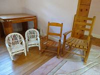 All four chairs (2 wicker and 2 wooden rockers) together on floor in room corner