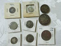 Nine old American coins displayed in holders with visible years 1857 and 1888 and various designs.