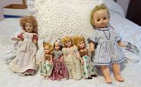 Seven dolls including various styled Irish, Nurse, Bride dolls, baby doll and painted doll on lace quilt background