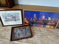 Wide shot showing all three framed prints arranged on a bed, including the Philadelphia skyline photo, vintage Elfreth's Alley print, and Valley Forge print.