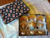 Gold lusterware child tea set in original floral box showing teapot, sugar bowl, creamer, cups and saucers with floral design