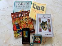 Photo showing the four tarot books and two tarot decks including The Animal-Wise Tarot book and box, and the medieval scapini tarot deck box and a mini tarot deck box.