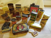 Photo showing a variety of antique metal tins and cans with colorful vintage labels from brands including Kellogg's, Postum, Band-Aid, Towles, McCormick's, French's, Bayer, and more.