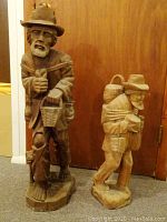 Two large hand-carved wooden peasant figures placed side by side showing size difference and intricate details.