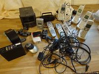 Multiple AT&T cordless phones with bases, remotes, clock radio/cd player, mouse, and power cords shown together on table