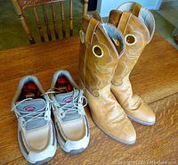 Photo showing both cowboy boots and deck shoes side by side on a wooden table.