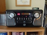 Front view of the stereo system showing volume and tuning knobs, digital display and radio dial.