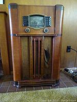 Full front view of walnut veneer console radio with speaker grille, pushbuttons and knobs