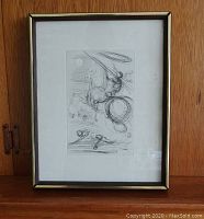 Full view of framed etching leaning against wooden backdrop