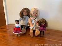 Four dolls on wooden surface, two large and two mini