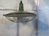 Side view of green metal dome light fixture showing wire protective cage and cord connection