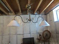 Full view of the twin-arm brass light fixture with two metal shades hanging