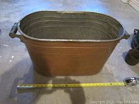 Top-side view of large copper boiler with measuring tape in front showing length approximately 26 inches.