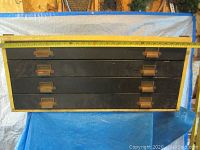 Front view of closed vintage plan cabinet showing four horizontal drawers with black fronts and brass handles and label holders, measuring approximately 33 inches wide.