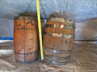 Photo of two vintage wooden barrels, one marked 'CNR', placed side by side with a measuring tape showing height.